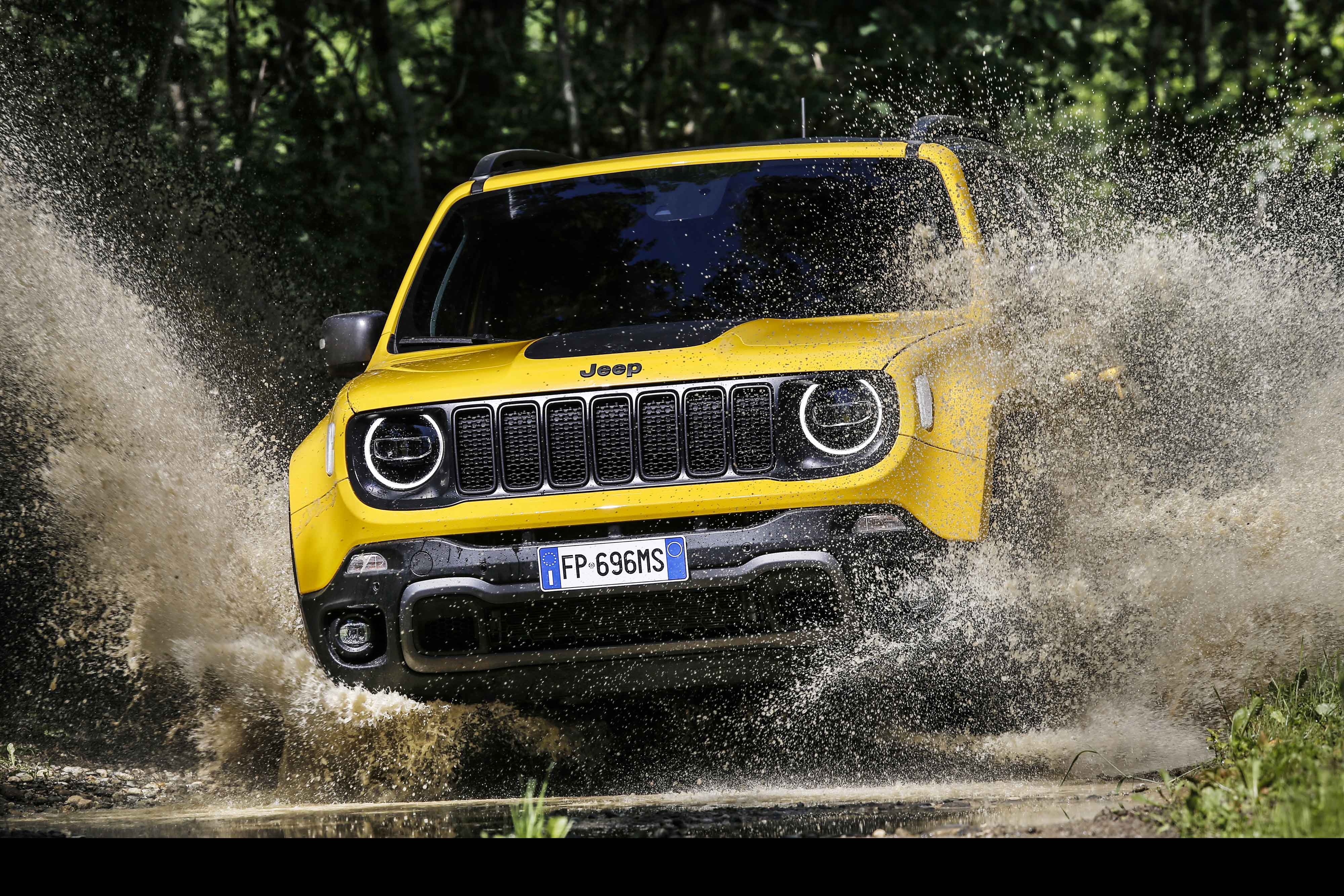Photo of a yellow Jeep crossing a ford with mud